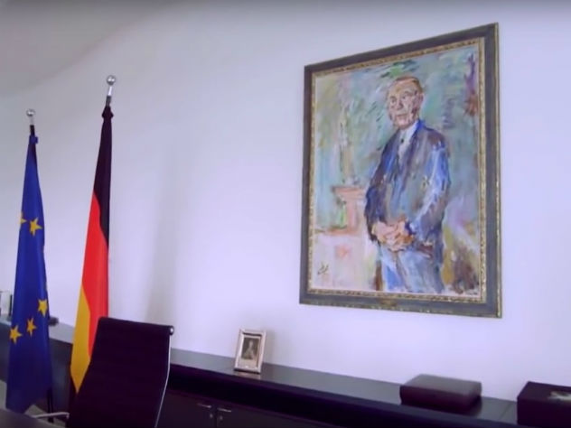 Над рабочим столом Меркель на стене висит портрет первого канцлера ФРГ Конрада Аденауэра. Фото: скриншот видео