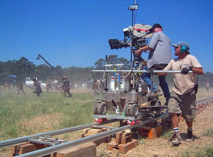 Дольщик управляет тележкой с кинооператором. На заднем плане кран со звукозаписывающей аппаратурой. Автор фото SeanDevine. Источник wikimedia.org