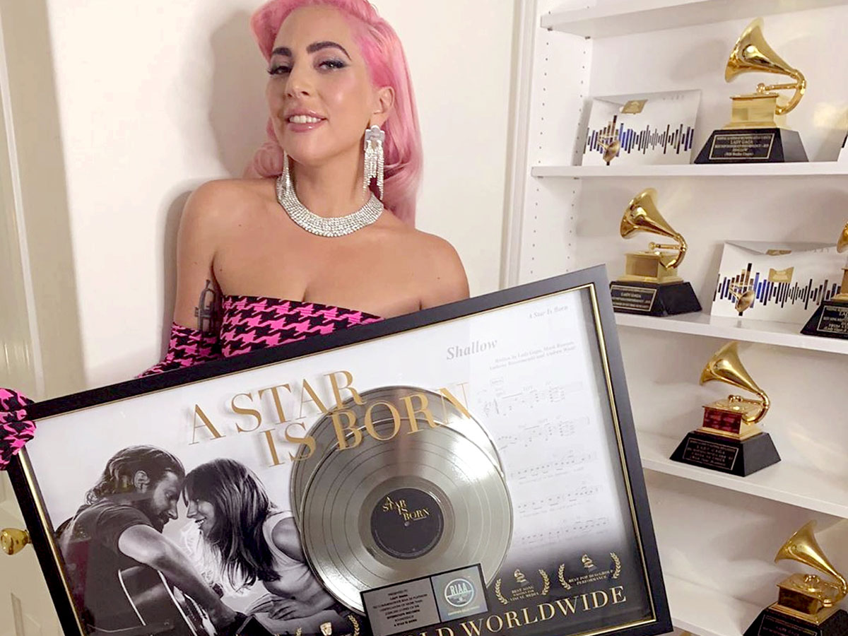 В руках певица держит памятную доску в честь Shallow, где все сказано